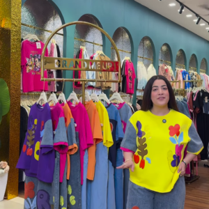 1205-4.png Multicolor Printed Ethnicwear Rack Display – Bold Floral & Abstract Garments in Boutique Interior with Teal-Gold Accents