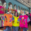 1205-5.png Multicolor Printed Ethnicwear Rack Display – Bold Floral & Abstract Garments in Boutique Interior with Teal-Gold Accents