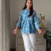 Women’s Sleeveless Red Floral Top with Light Blue Flared Jeans – Indo-Western Casualwear Styled with Vintage Decor Backdrop