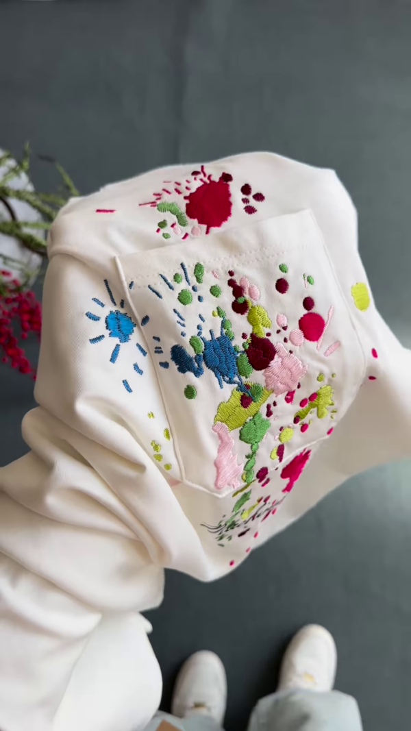 1209-2.png Unisex White & Beige T-Shirts with Colorful Paint Splatter and Pocket Embroidery – Artistic Casualwear for Everyday Styling